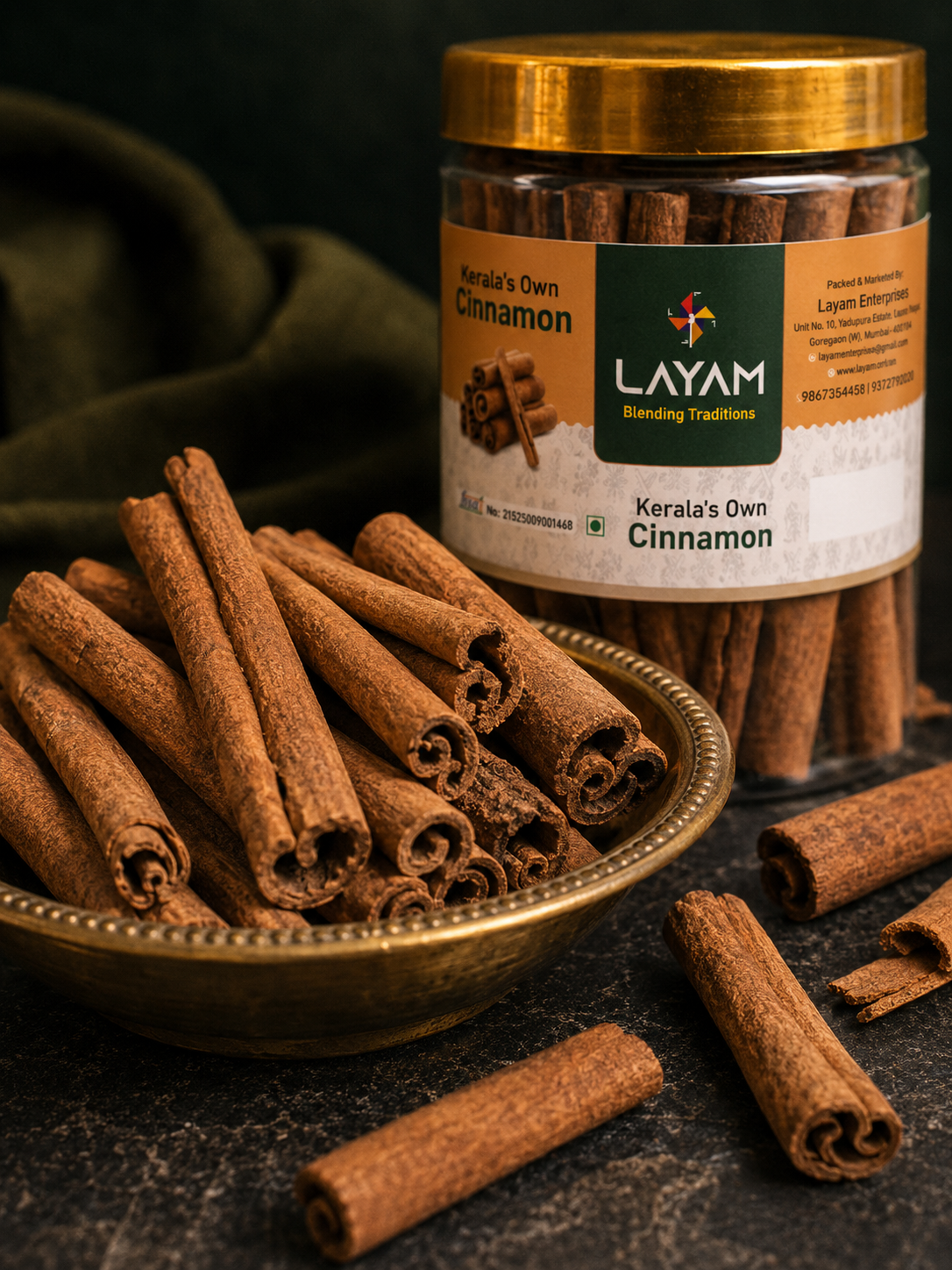 Close-up of hand-rolled Kerala cinnamon quills in a brass bowl beside the LAYAM jar