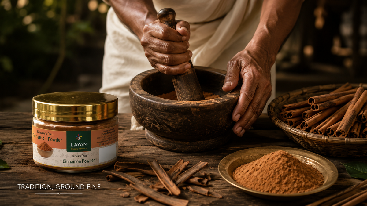 Cinnamon quills being ground by hand in a stone mortar and pestle, with the LAYAM powder jar alongside